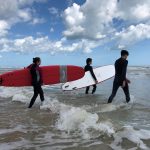 Three UCF Students enter the water in the Atlantic Ocean on a Learn to Surf trip.
