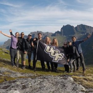 Students holding UCF flag on top of a mountain
